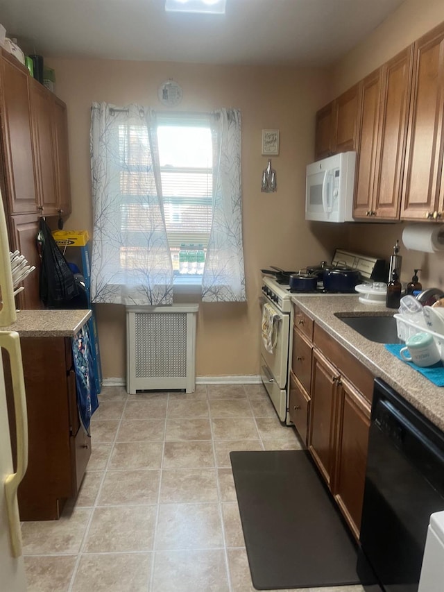 kitchen with white microwave, dishwasher, radiator heating unit, light tile patterned floors, and range with gas stovetop