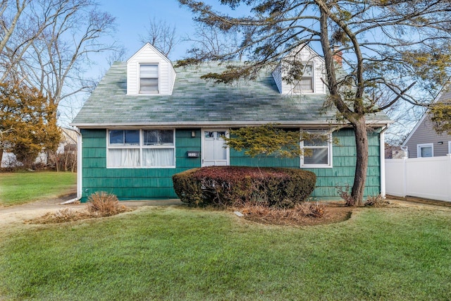 cape cod-style house featuring a front yard and fence