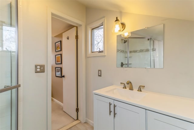 full bathroom featuring baseboards, a tile shower, and vanity