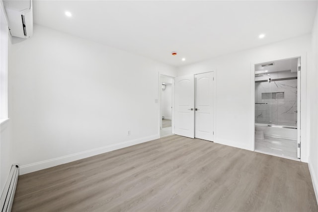 unfurnished bedroom featuring a baseboard radiator, baseboards, wood finished floors, and a wall mounted air conditioner