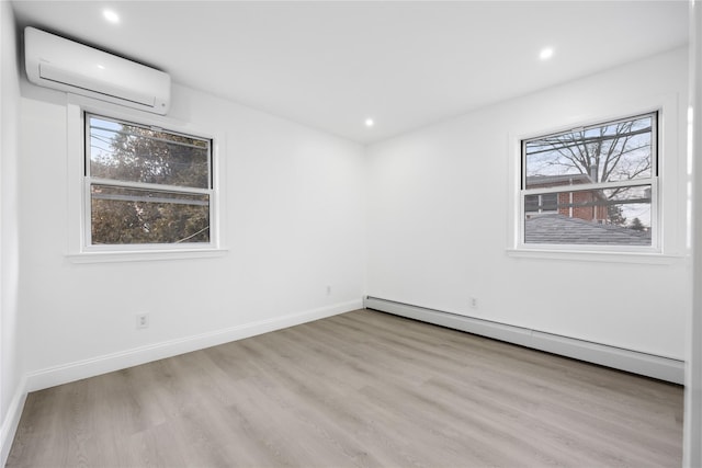 spare room with a wealth of natural light, a baseboard radiator, an AC wall unit, and wood finished floors