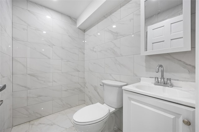 bathroom featuring toilet, a tile shower, vanity, and tile walls