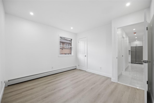 spare room featuring recessed lighting, baseboards, light wood finished floors, and baseboard heating