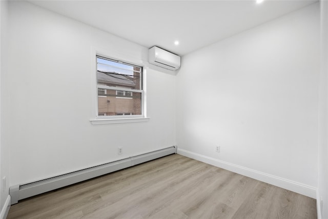 spare room featuring an AC wall unit, a baseboard radiator, wood finished floors, and baseboards