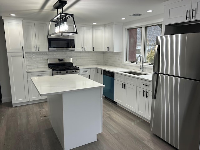 kitchen featuring stainless steel appliances, visible vents, decorative backsplash, a sink, and wood finished floors