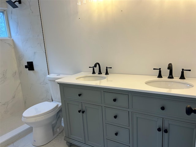 bathroom with tiled shower, a sink, toilet, and double vanity