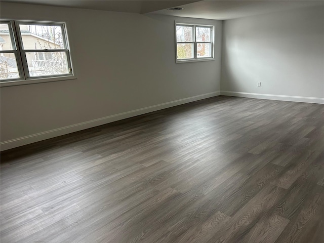 unfurnished room featuring visible vents, dark wood finished floors, and baseboards