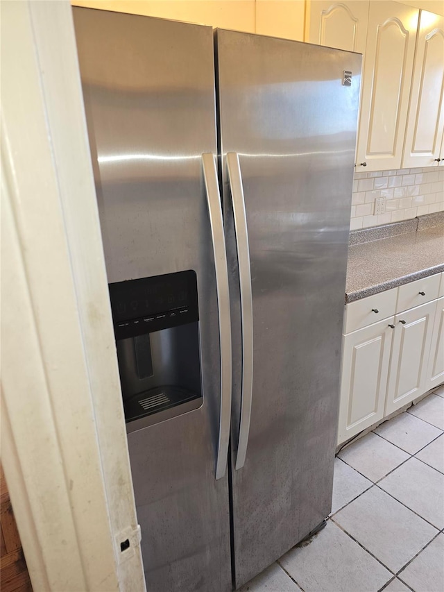 kitchen featuring white cabinets, stainless steel fridge, tasteful backsplash, and light tile patterned flooring