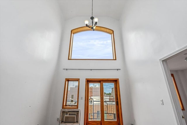 foyer entrance featuring lofted ceiling, a wall unit AC, and an inviting chandelier