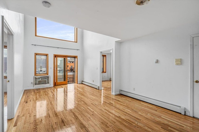 unfurnished living room with baseboards, a baseboard radiator, baseboard heating, an AC wall unit, and light wood-style floors