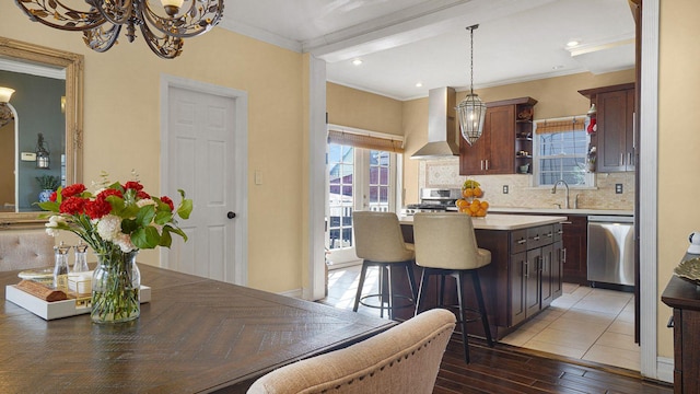 kitchen with appliances with stainless steel finishes, a sink, crown molding, and wall chimney exhaust hood