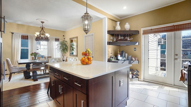 kitchen with pendant lighting, light countertops, ornamental molding, and an inviting chandelier