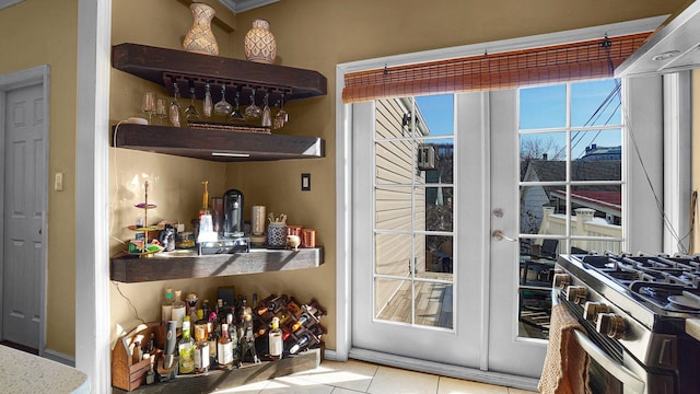 bar with baseboards, french doors, tile patterned floors, a dry bar, and gas stove