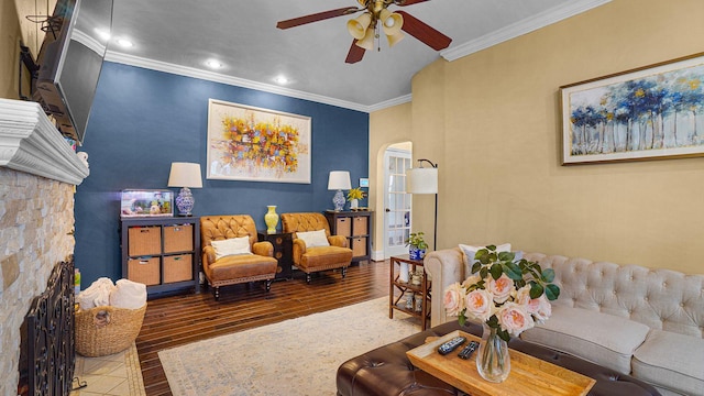 living room with a ceiling fan, arched walkways, wood finished floors, and ornamental molding