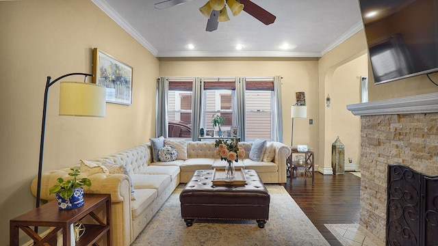 living room featuring ornamental molding, a fireplace, wood finished floors, and a ceiling fan