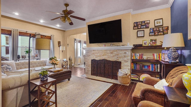 living area with crown molding, recessed lighting, a ceiling fan, a stone fireplace, and wood finished floors