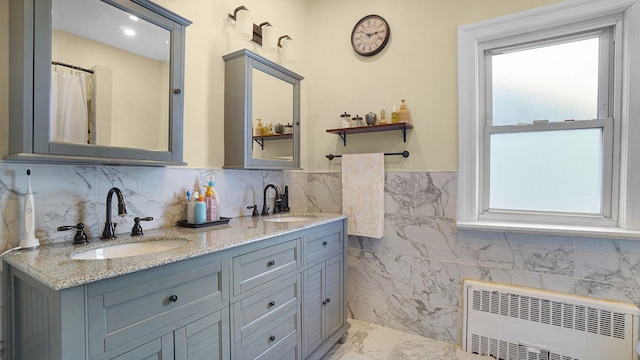 bathroom with marble finish floor, a healthy amount of sunlight, a sink, and radiator