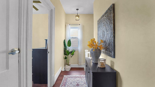 doorway to outside featuring baseboards and dark wood finished floors