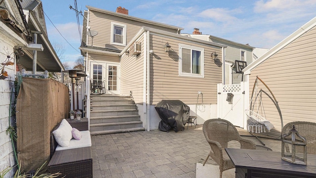 rear view of property featuring fence, french doors, a gate, a chimney, and a patio area