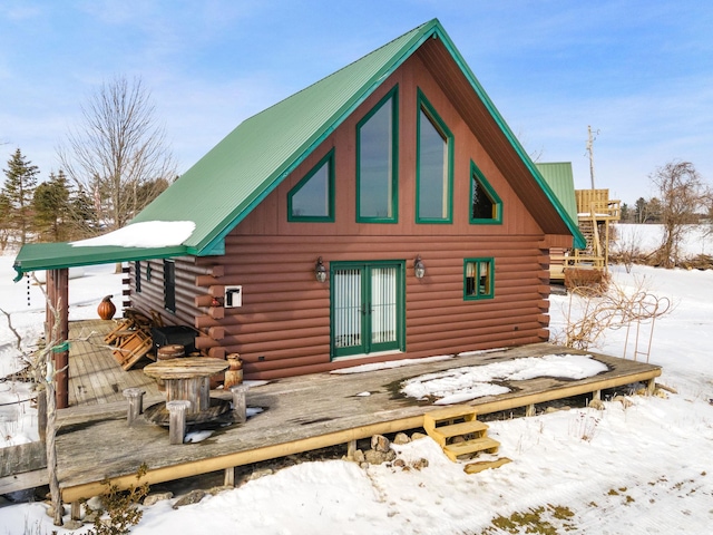 snow covered rear of property with french doors, metal roof, log exterior, and a wooden deck