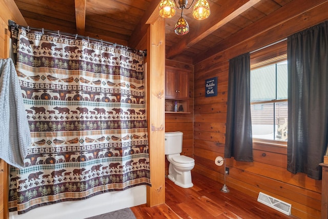 bathroom with wooden ceiling, toilet, wood walls, wood finished floors, and visible vents