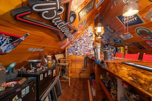 interior space featuring vaulted ceiling, wooden walls, and hardwood / wood-style flooring