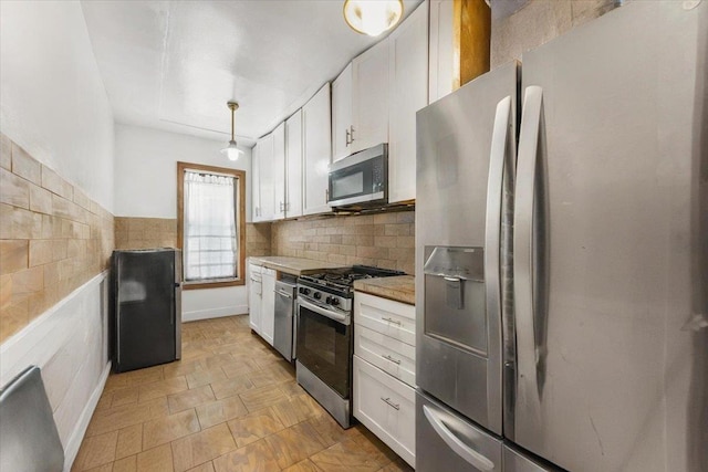 kitchen featuring decorative light fixtures, stainless steel appliances, light countertops, white cabinetry, and backsplash