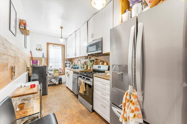 kitchen featuring a sink, white cabinetry, light countertops, appliances with stainless steel finishes, and decorative backsplash