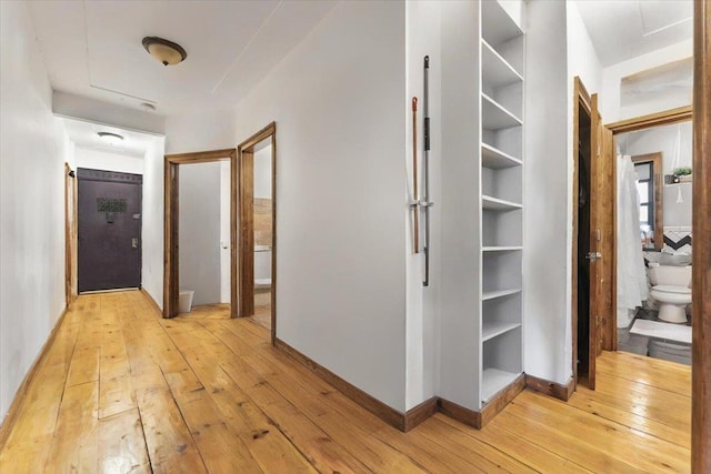 hall with light wood-style floors and baseboards