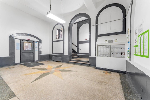 interior space featuring a high ceiling, mail area, and speckled floor