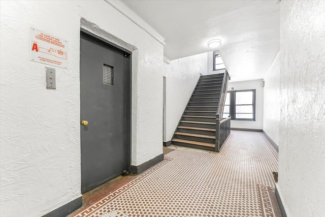 interior space featuring stairs, baseboards, and a textured wall