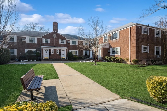 exterior space with brick siding, a chimney, and a front yard