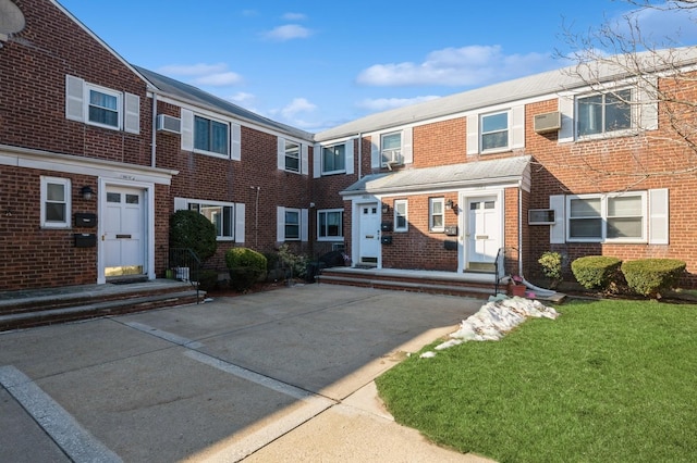 townhome / multi-family property with a front lawn and brick siding