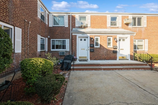 view of property featuring an AC wall unit and brick siding