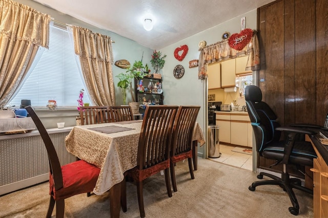 dining space featuring radiator, light tile patterned floors, and light carpet