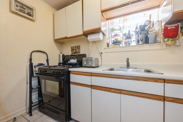 kitchen with light countertops, a sink, black gas stove, and white cabinetry