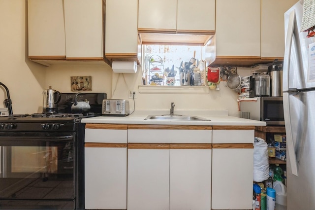 kitchen featuring light countertops, stainless steel microwave, a sink, and black range with gas stovetop