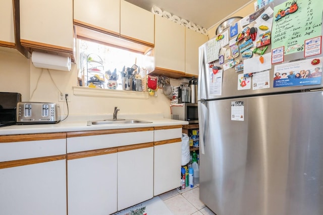 kitchen featuring a sink, light tile patterned floors, stainless steel appliances, and light countertops