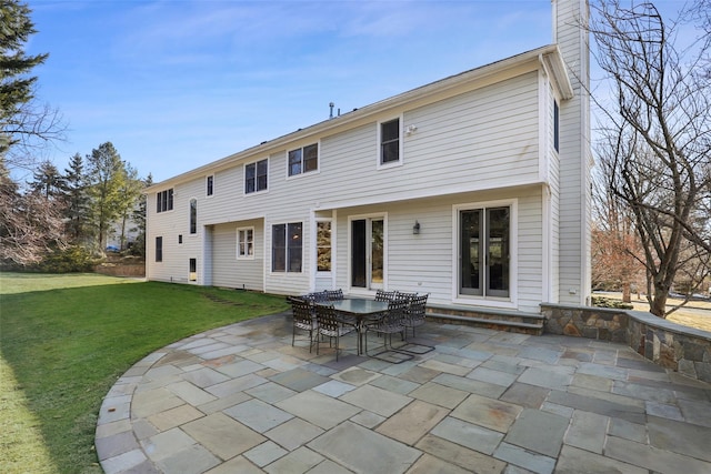 rear view of house with a patio, a lawn, and a chimney