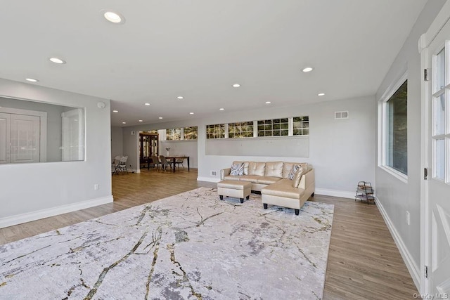 living room with baseboards, wood finished floors, visible vents, and recessed lighting