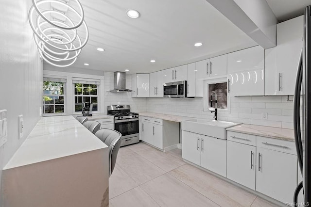 kitchen with tasteful backsplash, wall chimney exhaust hood, white cabinets, and stainless steel appliances