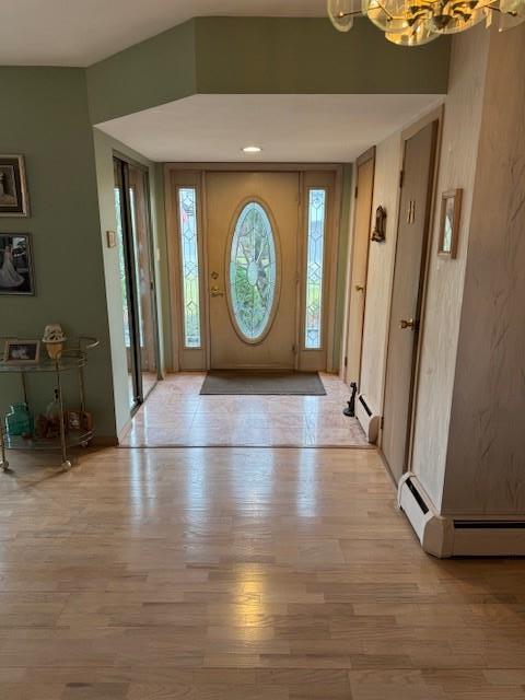 entryway with baseboard heating, a notable chandelier, and light wood finished floors