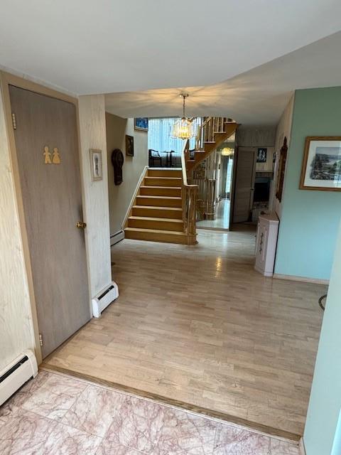 entryway with stairway, baseboard heating, and wood finished floors