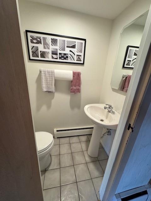 half bath featuring a baseboard radiator, a sink, toilet, and tile patterned floors