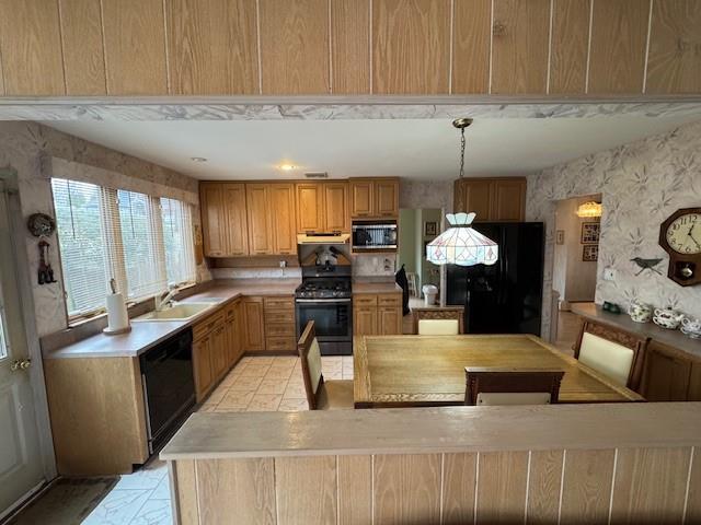 kitchen with black appliances, exhaust hood, a sink, and light countertops