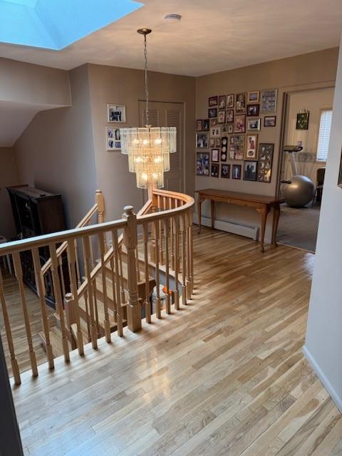 interior space with a baseboard radiator, wood finished floors, and an inviting chandelier