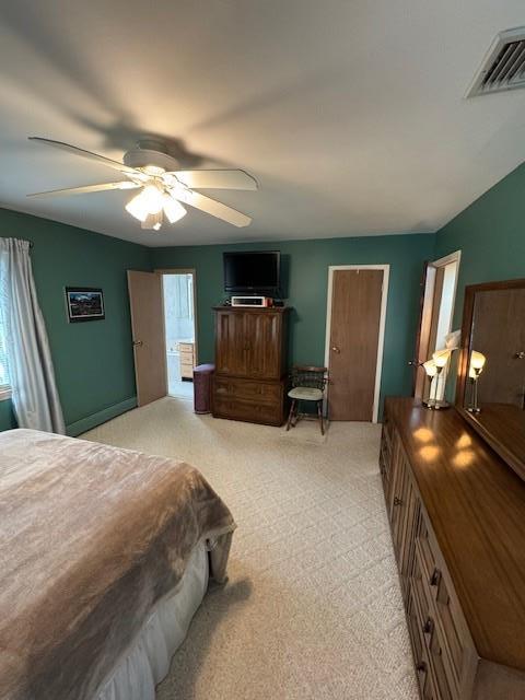 bedroom with a ceiling fan, visible vents, and light carpet