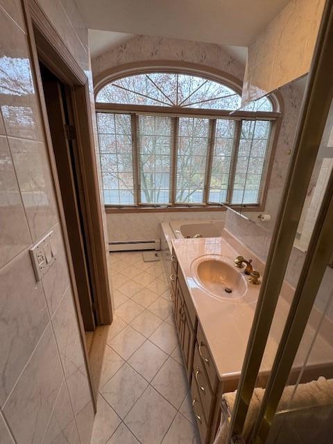 bathroom with a baseboard heating unit, a wealth of natural light, vanity, and tile patterned floors