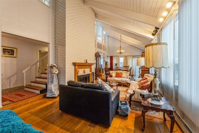 living area featuring beam ceiling, a fireplace, a chandelier, hardwood / wood-style floors, and stairs