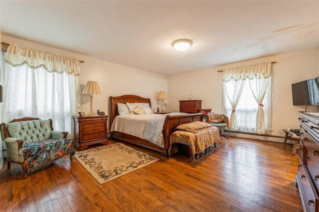 bedroom with a baseboard heating unit and hardwood / wood-style flooring